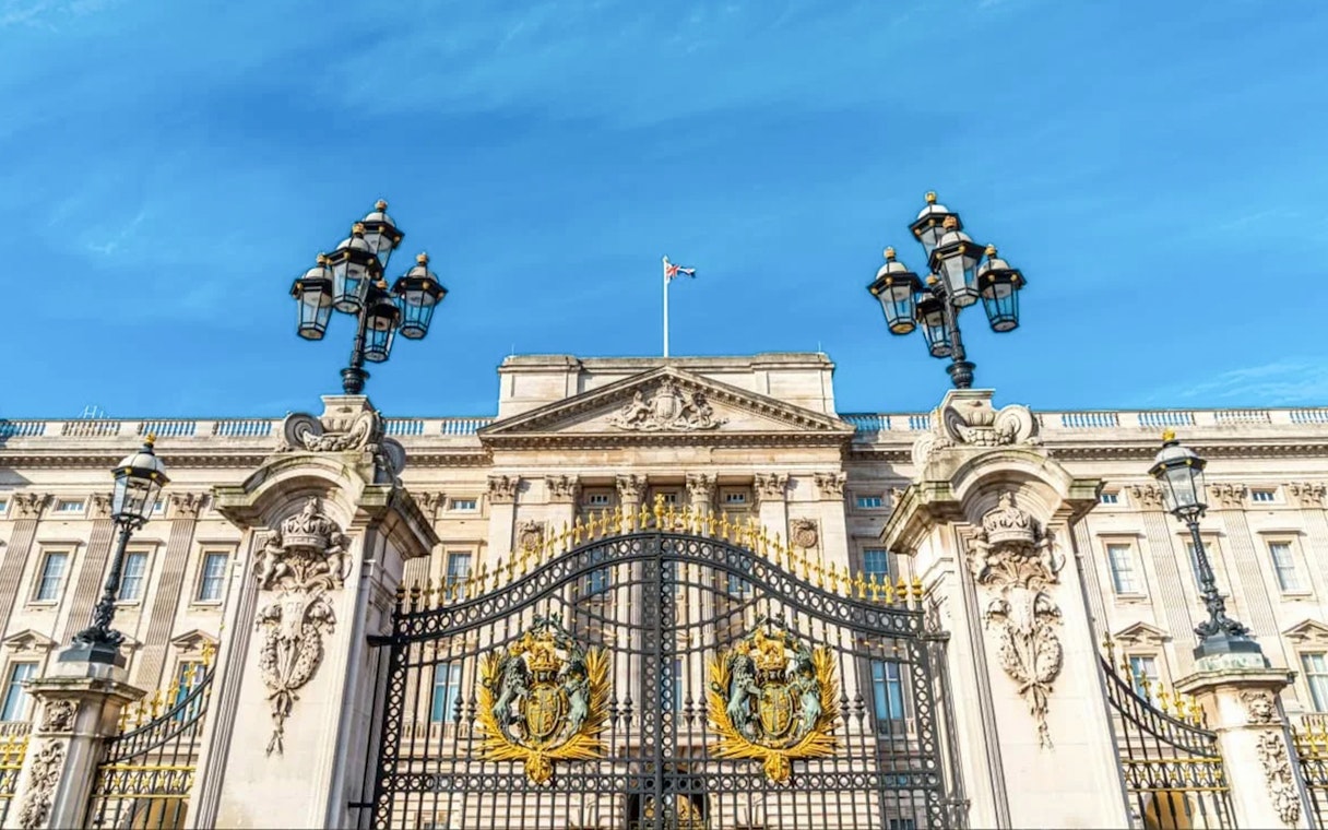 Buckingham Palace gates and facade under a clear blue sky, London.