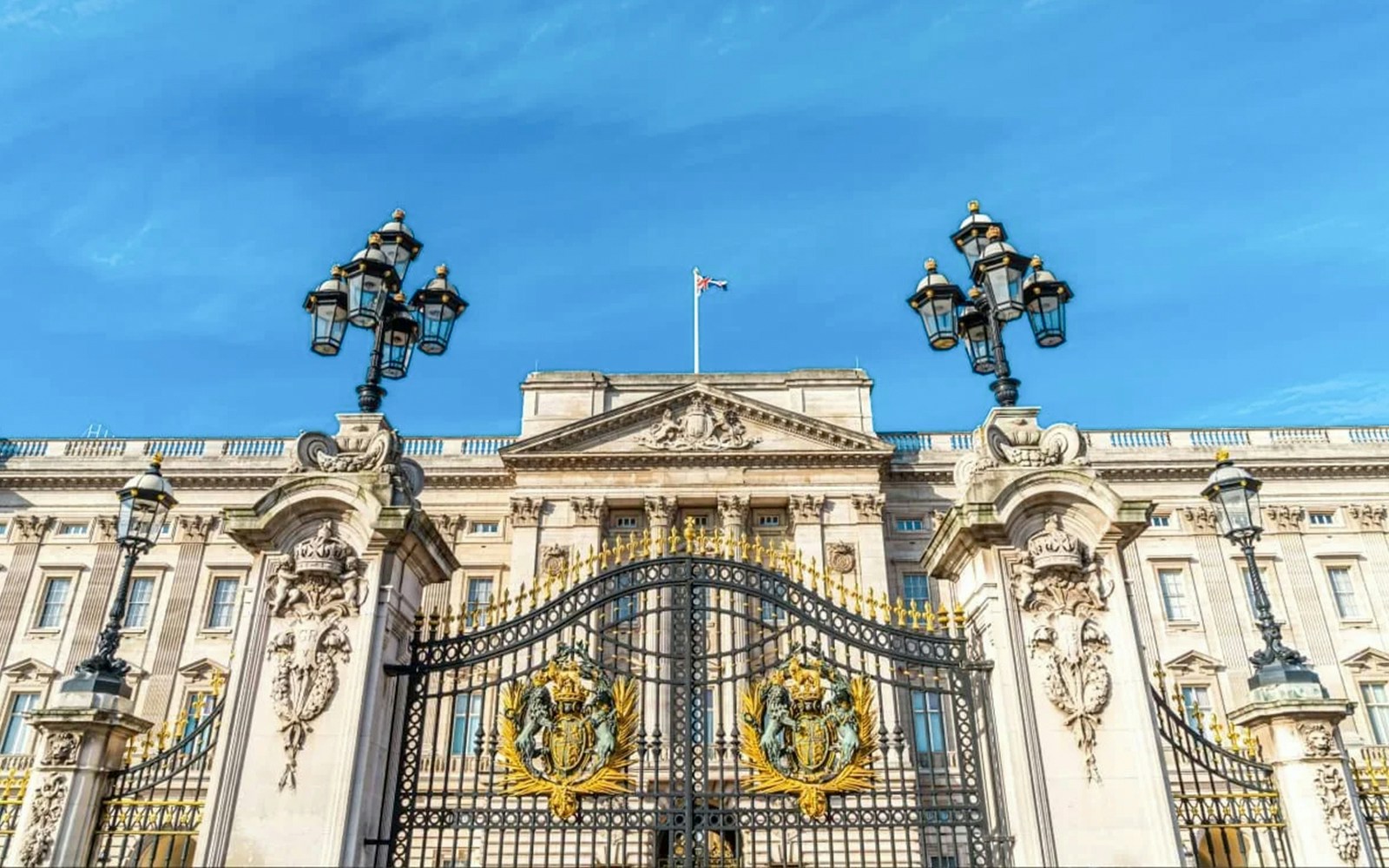 Buckingham Palace gates and facade under a clear blue sky, London.