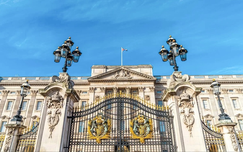 Buckingham Palace gates and facade under a clear blue sky, London.