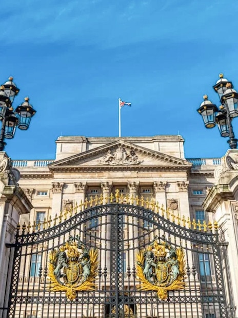 Buckingham Palace gates and facade under a clear blue sky, London.