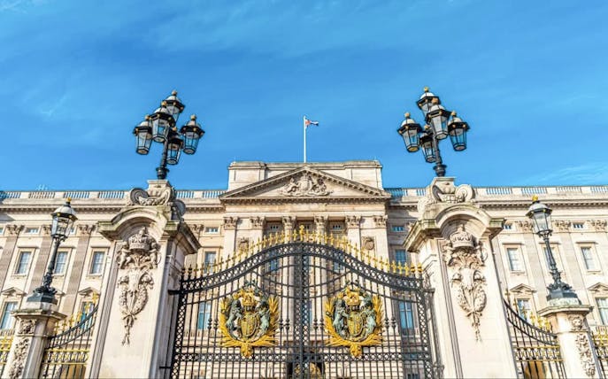 Buckingham Palace gates and facade under a clear blue sky, London.
