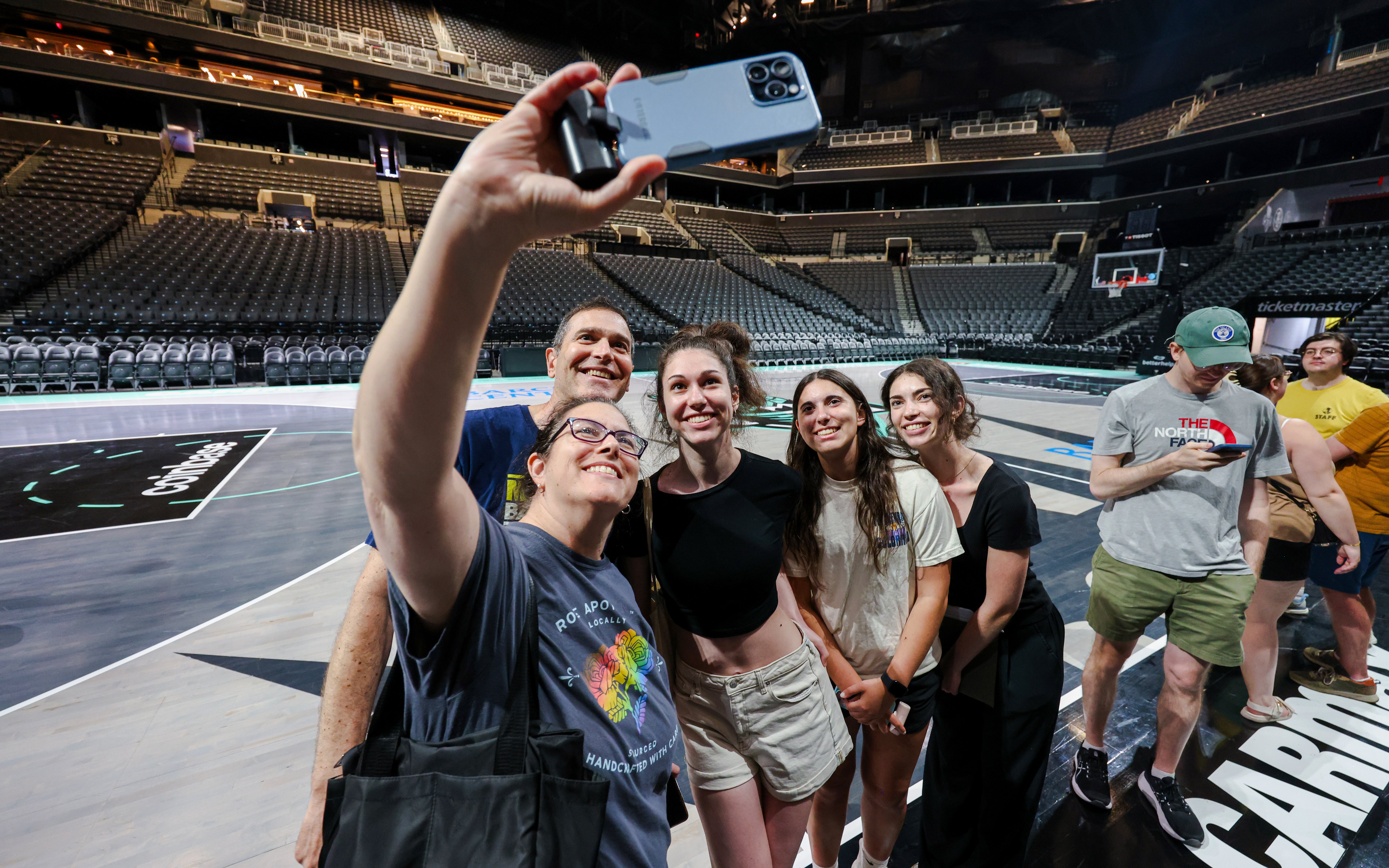 Group taking selfie on Barclays Center basketball court during guided tour, New York.