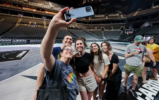 Group taking selfie on Barclays Center basketball court during guided tour, New York.