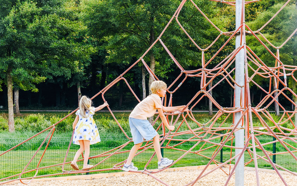 Children climbing a rope structure in a park near Chateau of Chantilly.