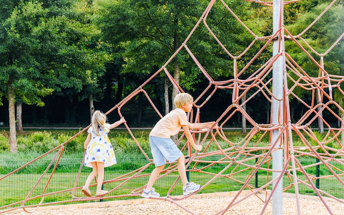 Children climbing a rope structure in a park near Chateau of Chantilly.