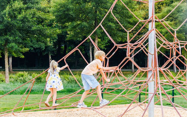 Children climbing a rope structure in a park near Chateau of Chantilly.