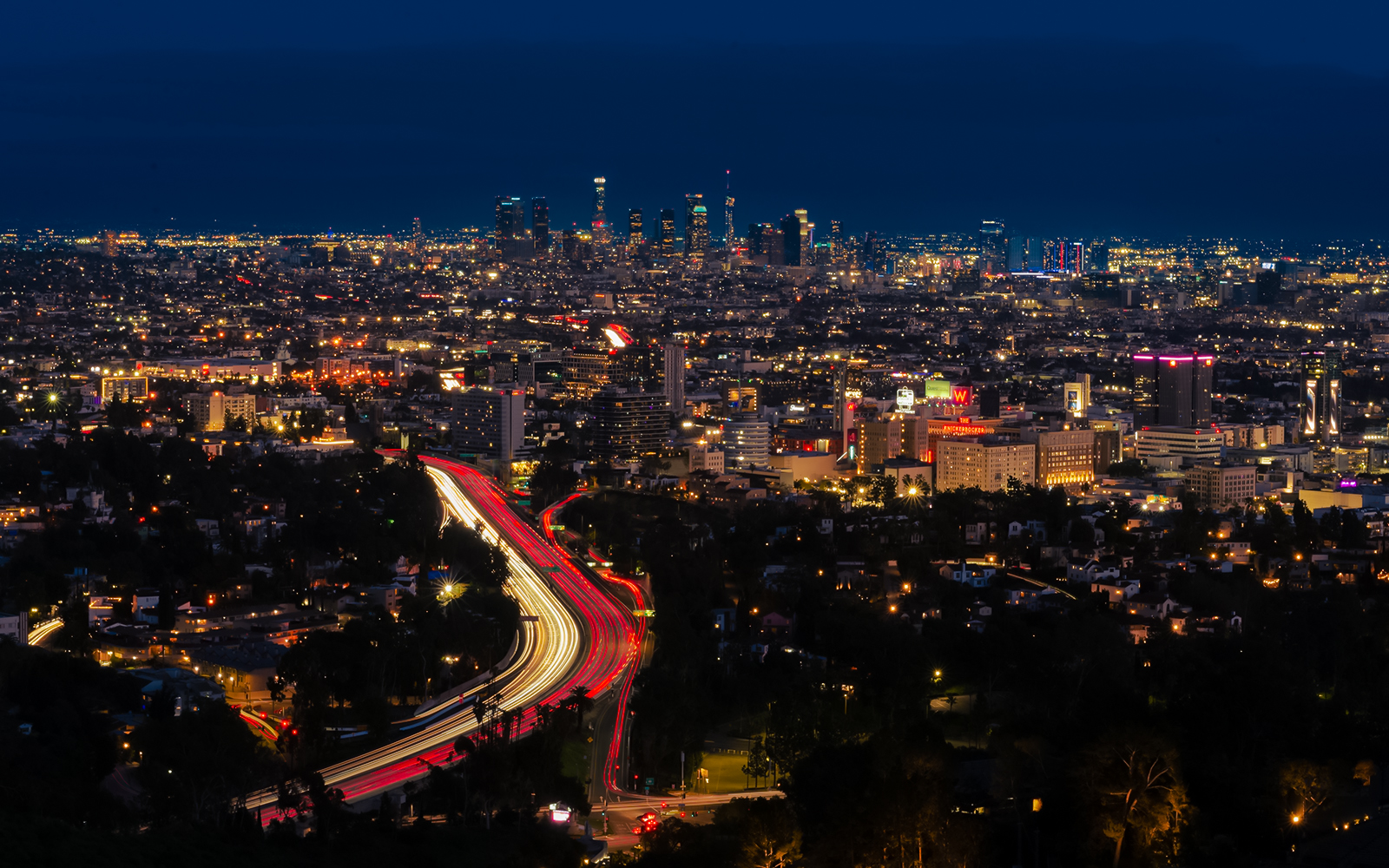 Los Angeles cityscape at night with illuminated skyline near Hollywood Bowl.