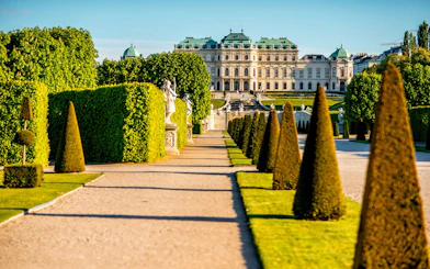 Upper Belvedere Palace gardens with statues and manicured hedges, Vienna.