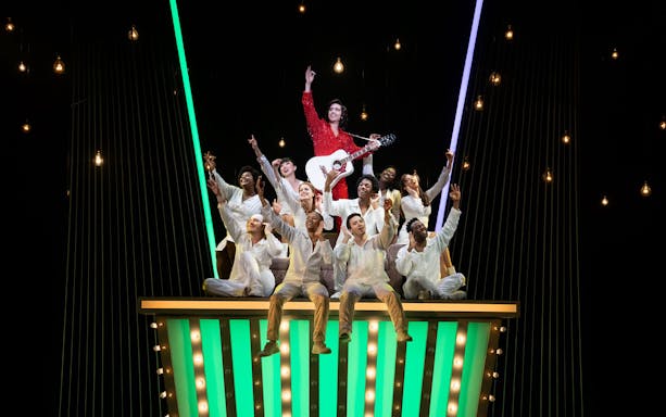 Performers on stage during "A Beautiful Noise: The Neil Diamond Musical" with a guitarist in a red outfit.