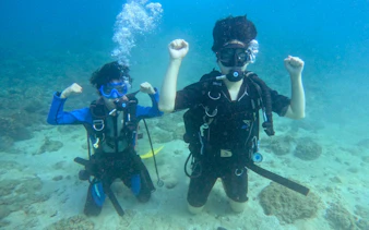 Scuba divers underwater in Fujairah, showing excitement during a diving experience.