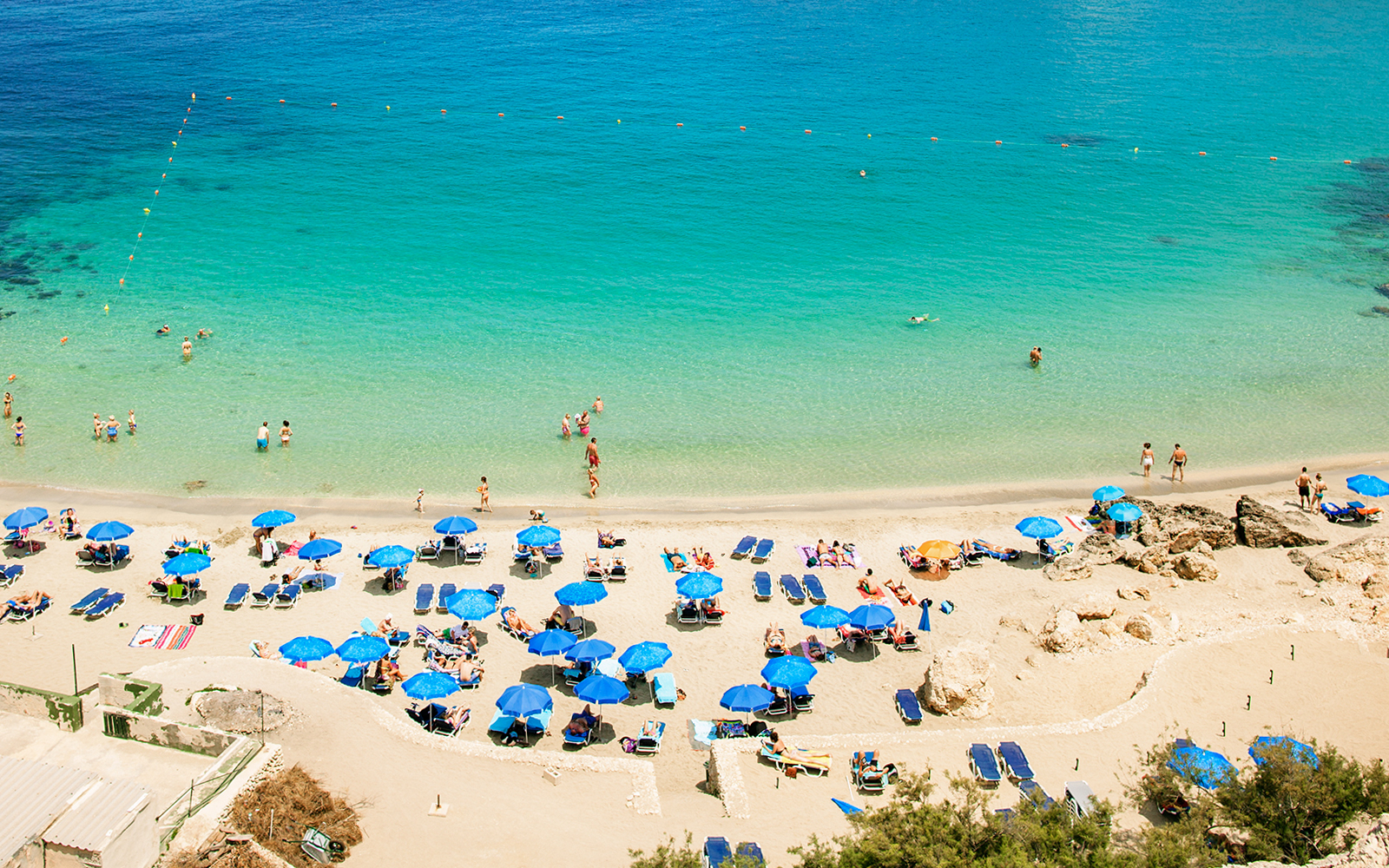 Golden sand beach with clear blue waters and sunbathers in Malta.