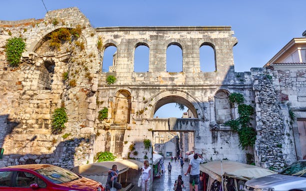 Diocletian's Palace gate in Split with tourists walking below.