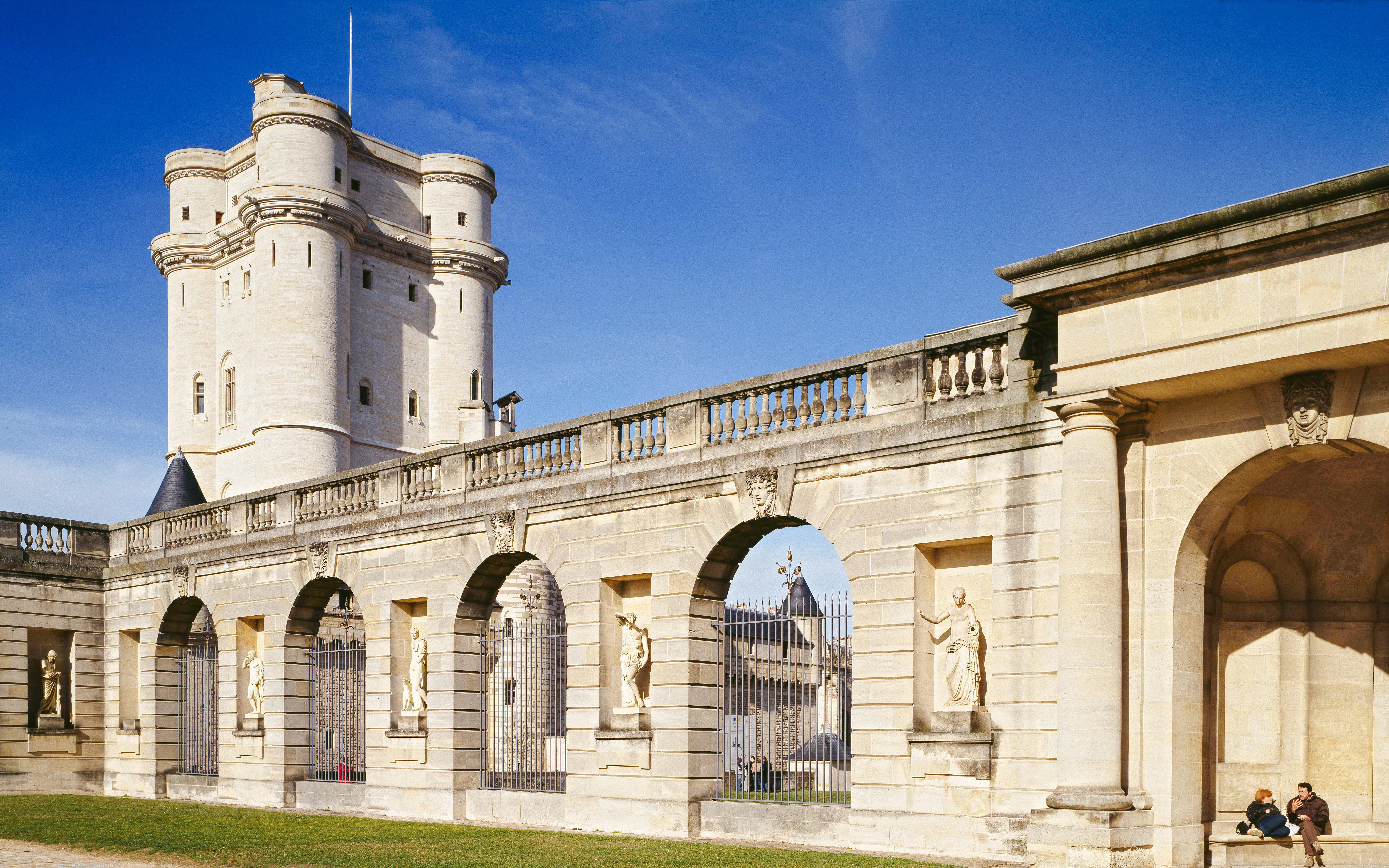 Château de Vincennes stone tower and arched wall with statues in Paris, France.