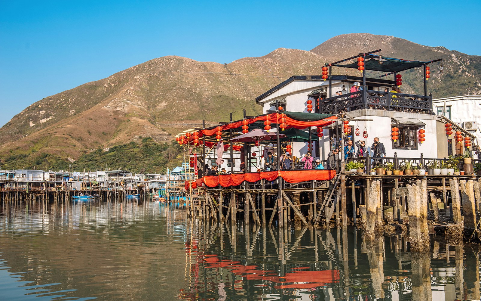 Stilt houses with red lanterns in Tai O fishing village, Hong Kong, viewed from the water.