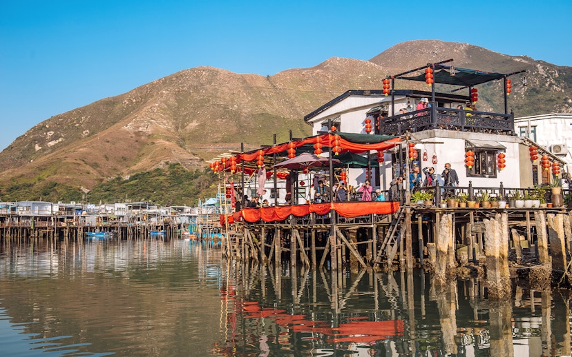 Stilt houses with red lanterns in Tai O fishing village, Hong Kong, viewed from the water.