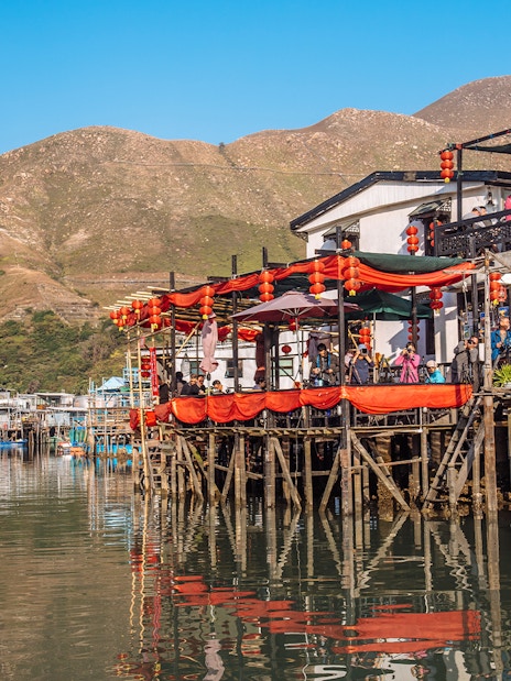 Stilt houses with red lanterns in Tai O fishing village, Hong Kong, viewed from the water.