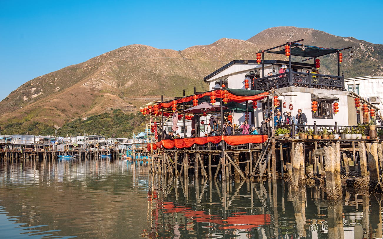 Stilt houses with red lanterns in Tai O fishing village, Hong Kong, viewed from the water.