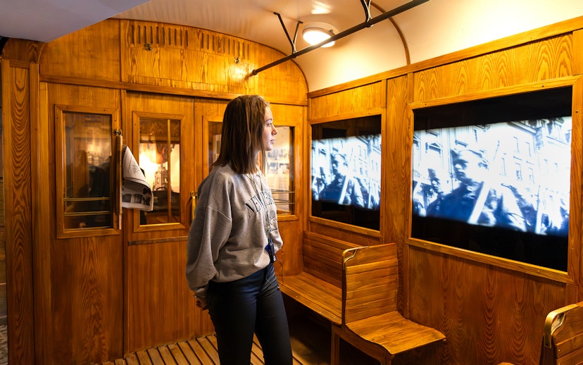 Train station exhibit inside Oskar Schindler's Factory with visitor watching historical footage.