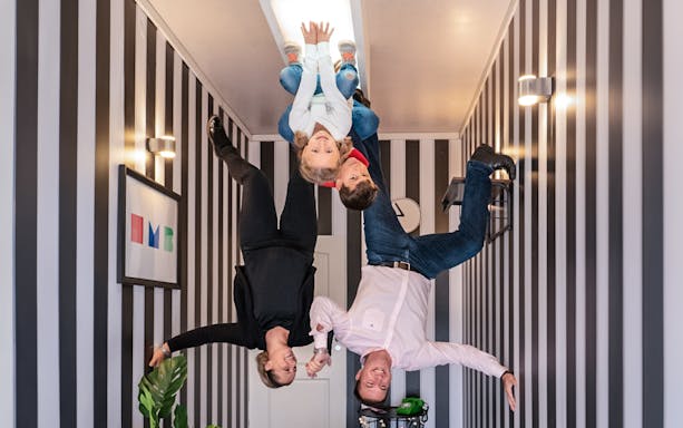 Visitors experiencing an upside-down room at Illuseum Berlin.