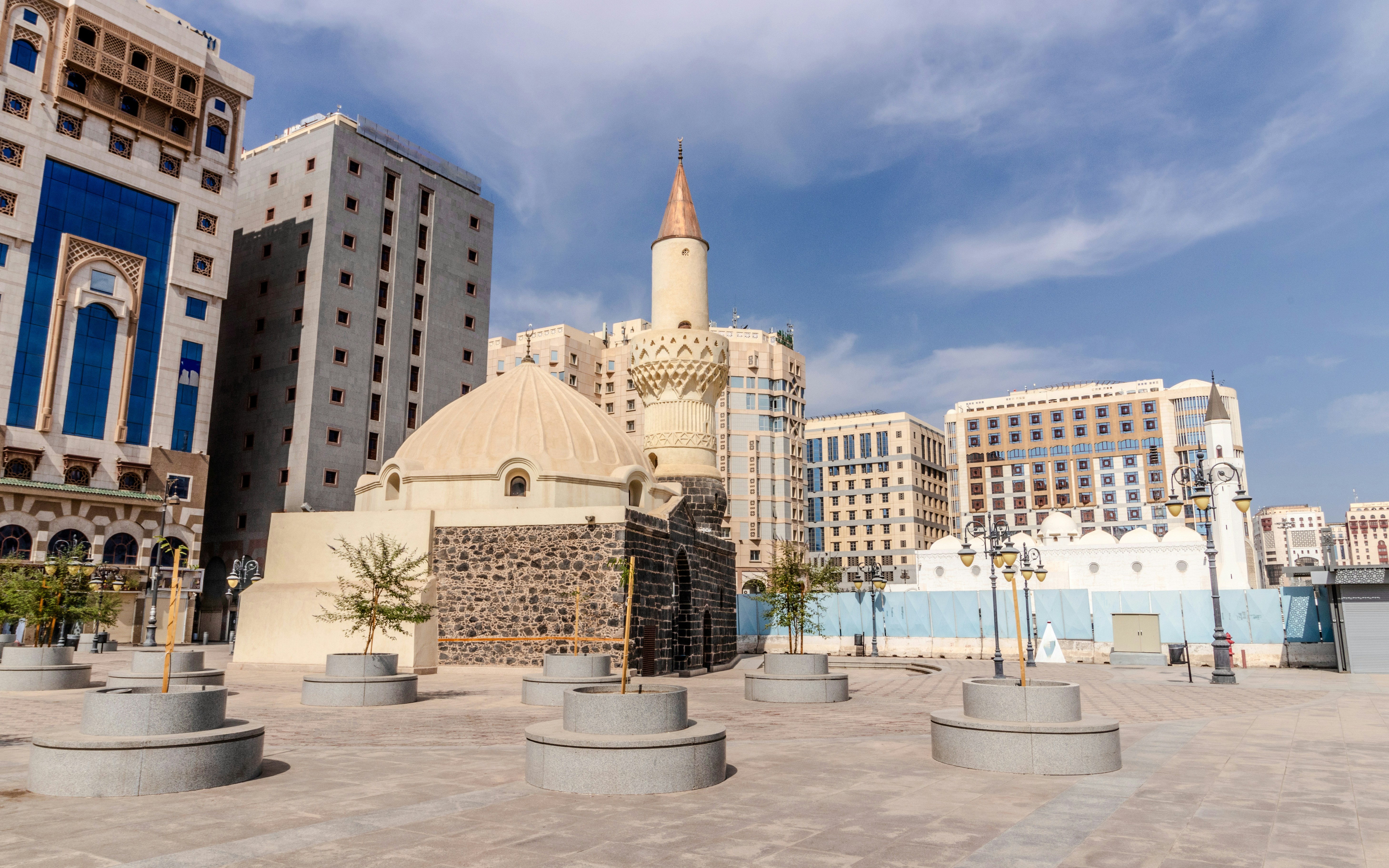 Abu Bakr Mosque with minaret in Al Haram area, Medina, Saudi Arabia, surrounded by modern buildings.