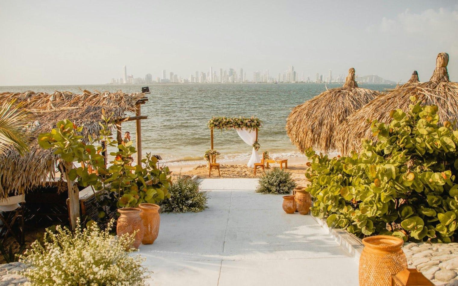 Vista Mare Beach House beachfront view with thatched huts and Cartagena skyline, Colombia.