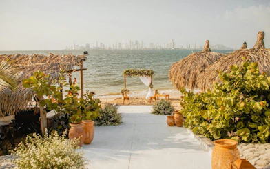 Vista Mare Beach House beachfront view with thatched huts and Cartagena skyline, Colombia.