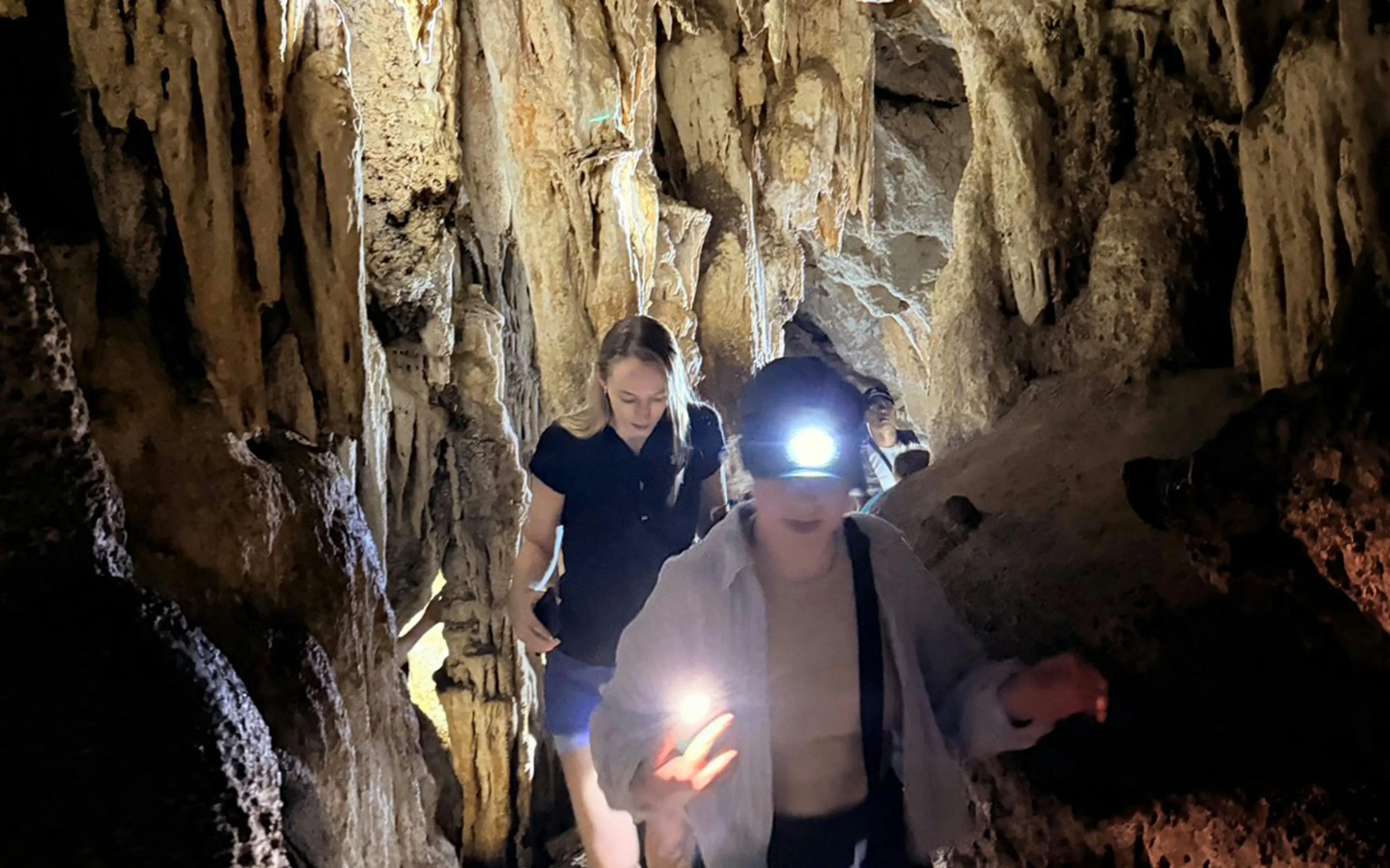 Visitors exploring Diamond Cave with headlamps on the Cheow Lan Lake tour in Krabi.