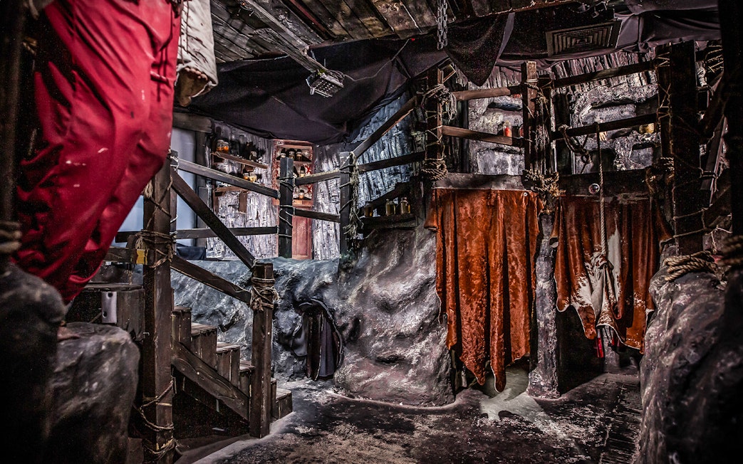 Cannibal Cave interior at Edinburgh Dungeon with rustic wooden stairs and eerie decor.