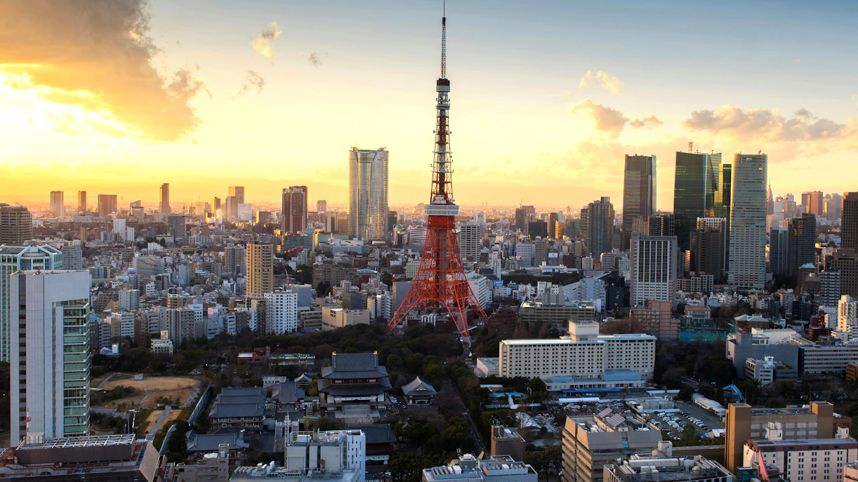 Tokyo Tower surrounded by cityscape at sunset.