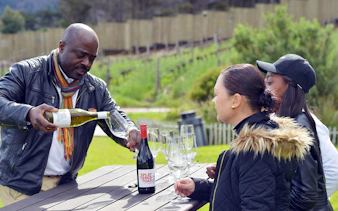 Guide pouring wine for guests at a vineyard in Constantia.