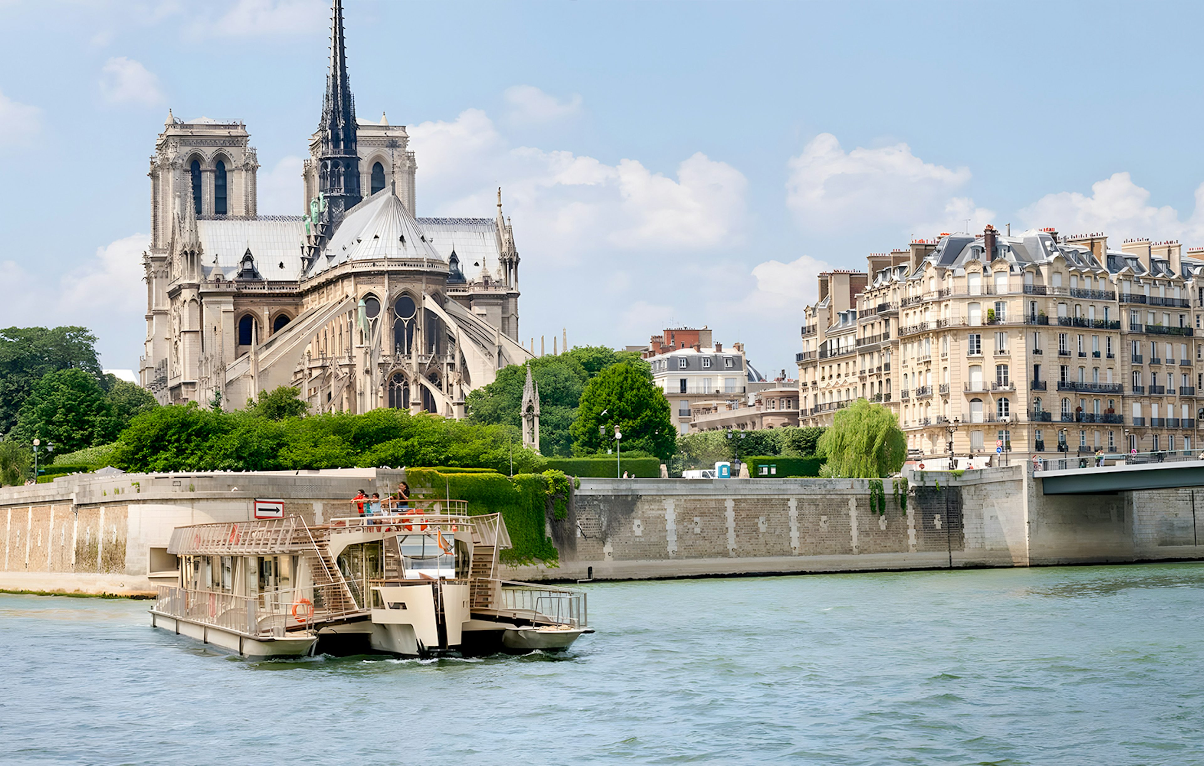 Seine River cruise boat passing Notre-Dame Cathedral in Paris.
