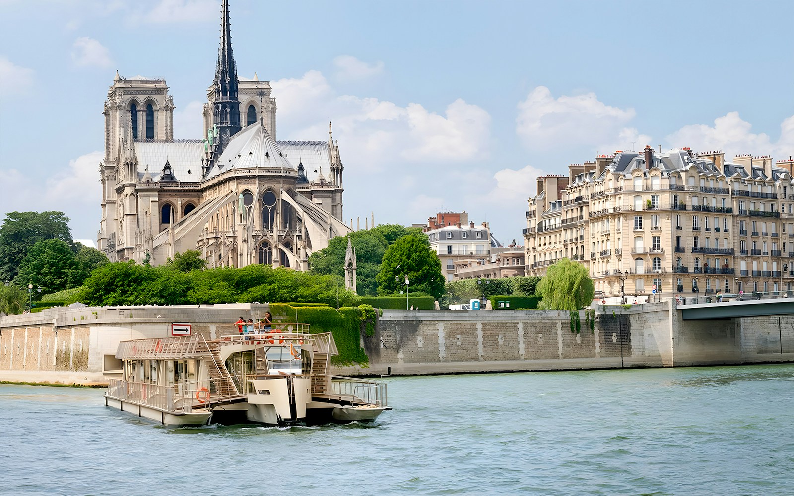 Seine River cruise boat passing Notre-Dame Cathedral in Paris.