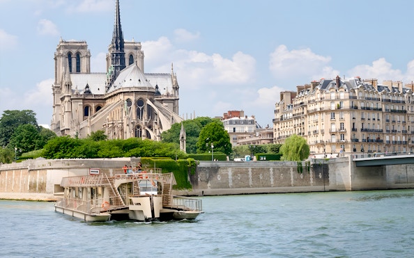Seine River cruise boat passing Notre-Dame Cathedral in Paris.