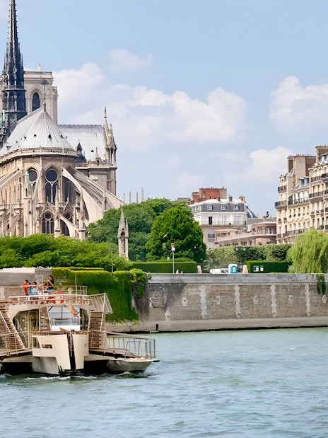 Seine River cruise boat passing Notre-Dame Cathedral in Paris.