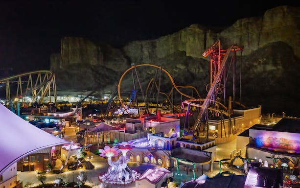 Roller coasters and attractions illuminated at night in Six Flags Qiddiya City, Saudi Arabia.