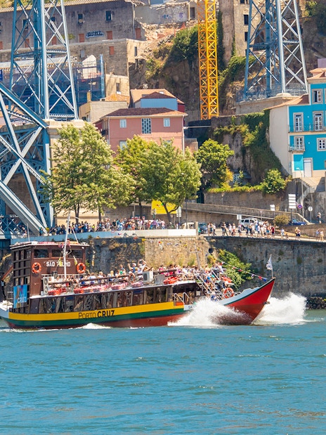Tour boat on Douro River near Dom Luís I Bridge in Porto, Portugal.