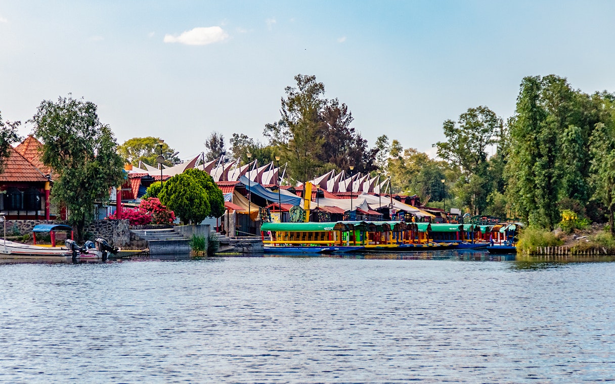 Xochimilco canals with colorful boats and floating gardens in Mexico City at sunset.
