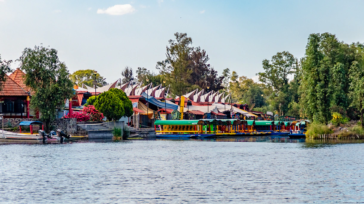 Xochimilco canals with colorful boats and floating gardens in Mexico City at sunset.