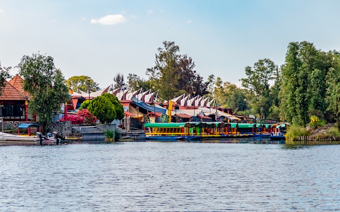 Xochimilco canals with colorful boats and floating gardens in Mexico City at sunset.
