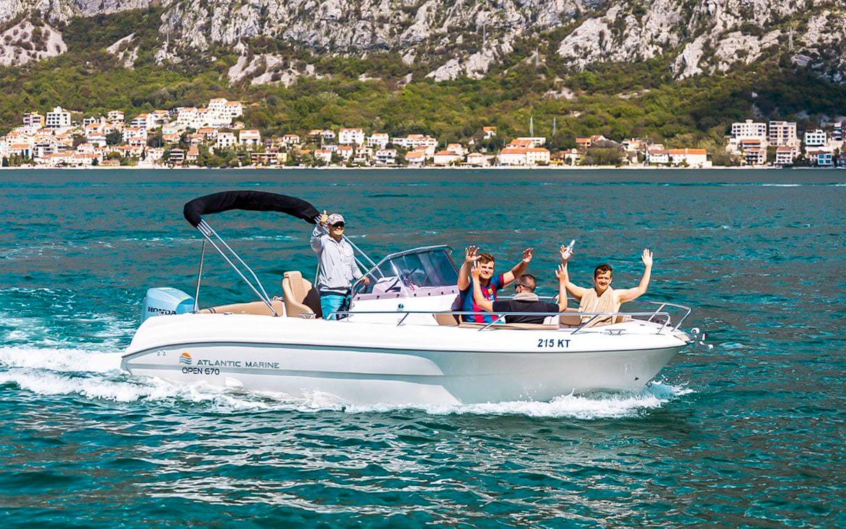 Guests waving on a speedboat during the Blue Caves tour with coastal town in the background.