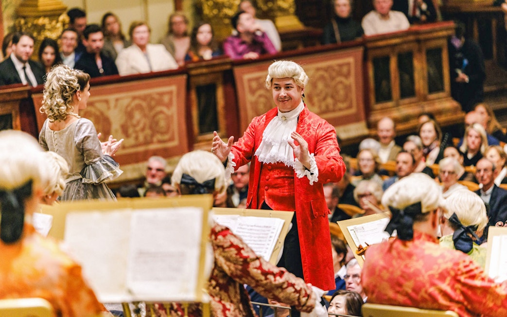 Mozart Orchestra performing in Vienna's Golden Hall with audience in period attire.