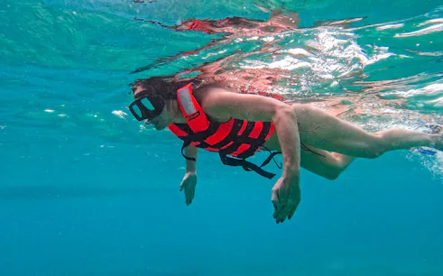 Snorkeler in Tulum waters wearing a life vest, exploring sea life.