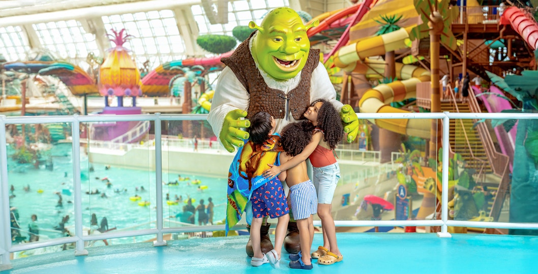 Kids hugging a character at Forbidden Waters pool, American Dream DreamWorks Water Park.