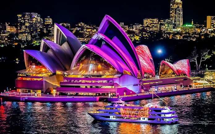 Cruise ship near illuminated Sydney Opera House during Vivid Sydney festival.