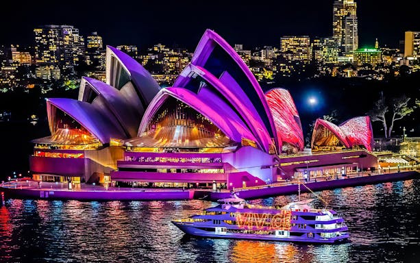 Cruise ship near illuminated Sydney Opera House during Vivid Sydney festival.