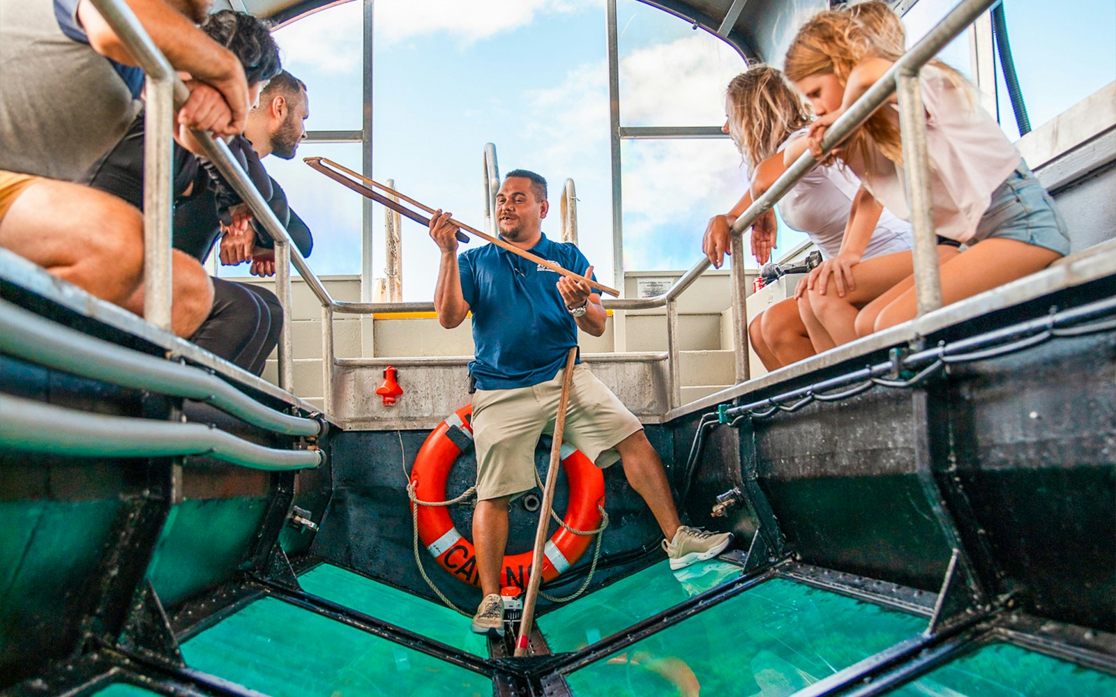 Guide explaining marine life on a glass bottom boat tour, Cairns to Great Barrier Reef.