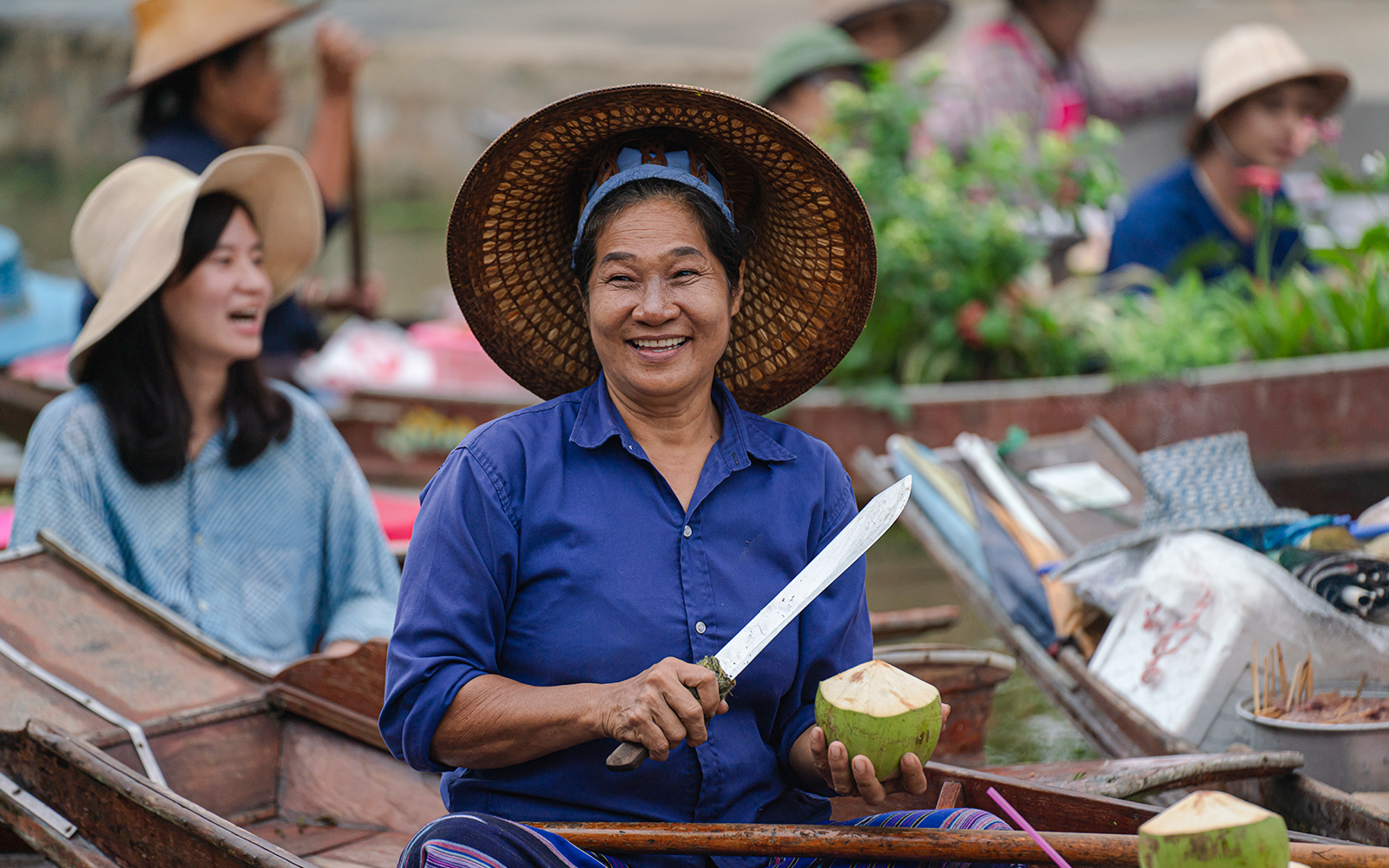 Middle age woman selling coconuts at Tha Kha floating market