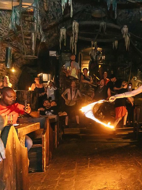 Fire dancer performing at a medieval-themed dinner with an audience in a stone-walled venue.