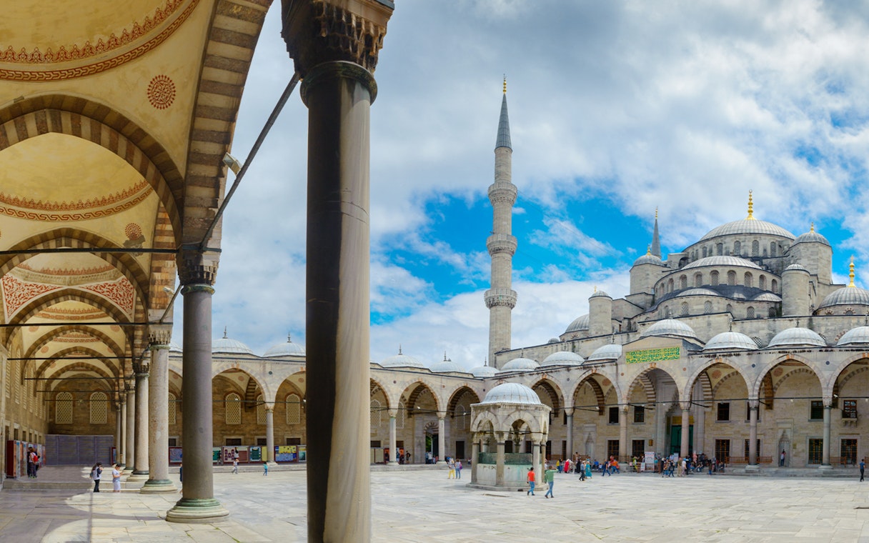 Courtyard of the Blue Mosque in Istanbul with arches and central fountain.