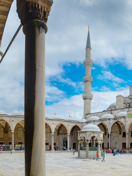 Courtyard of the Blue Mosque in Istanbul with arches and central fountain.